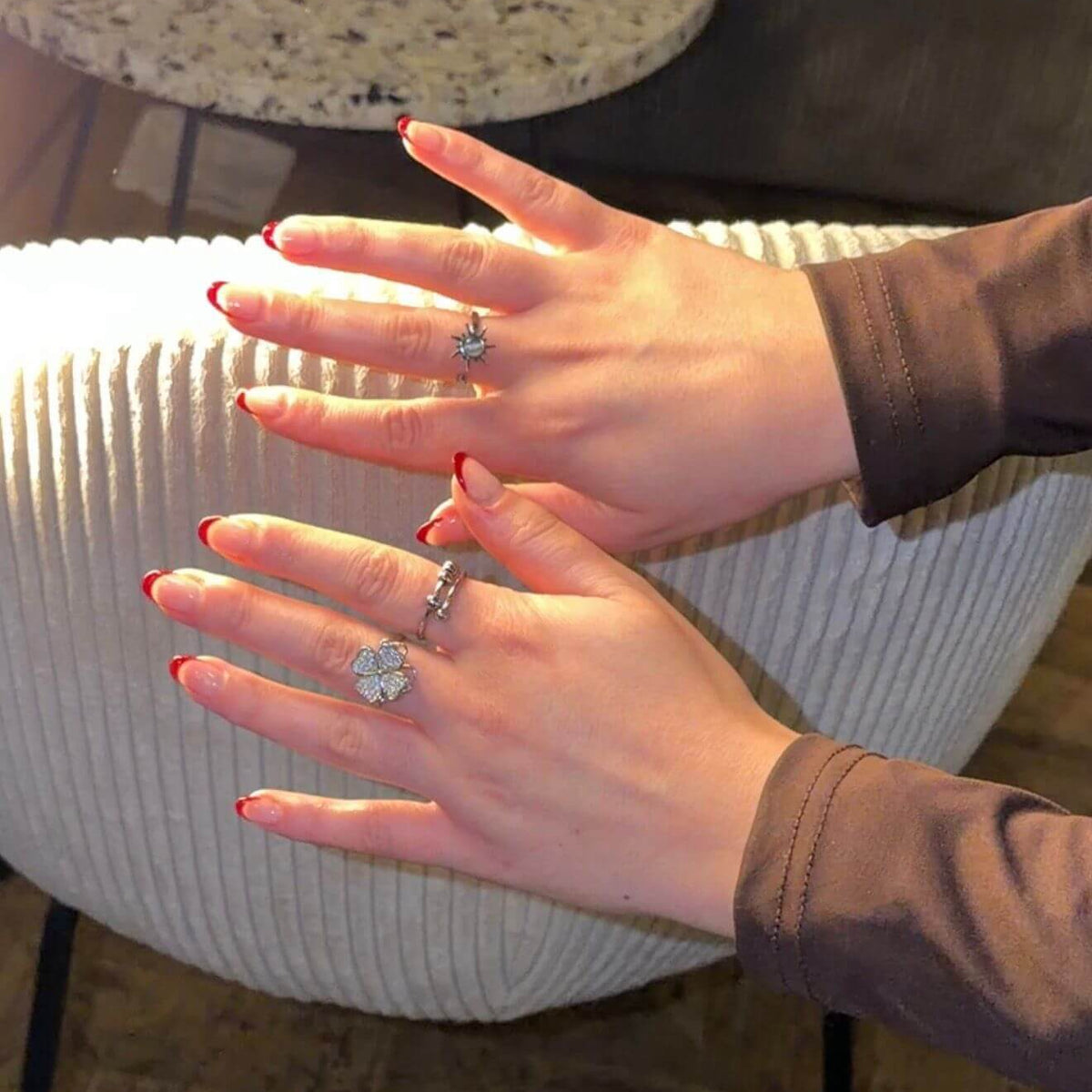 Close-up of two hands with rings on a textured surface