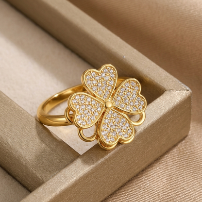 Gold four-leaf clover ring with diamonds on a beige jewelry box