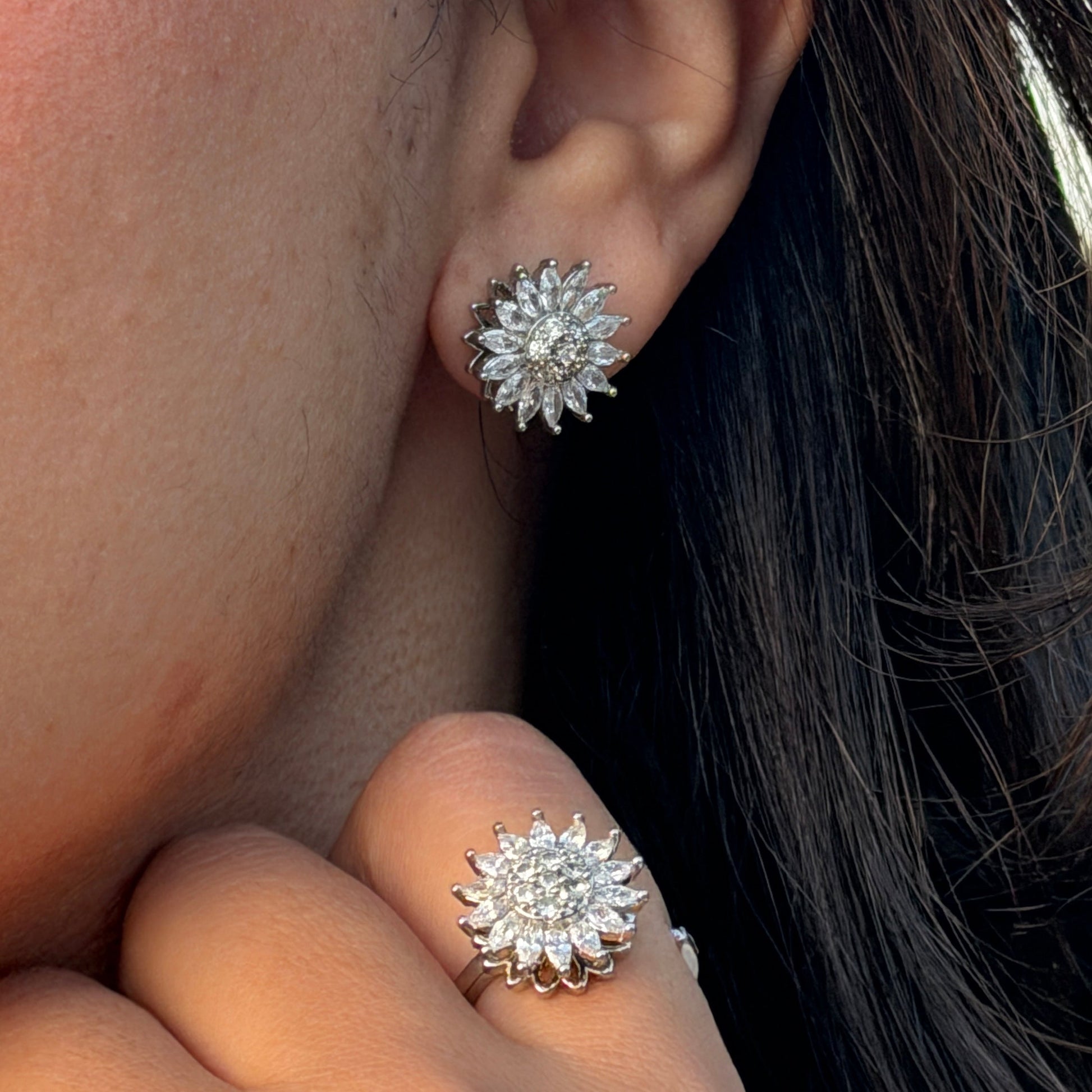 Close-up of a person wearing diamond stud earrings and ring.