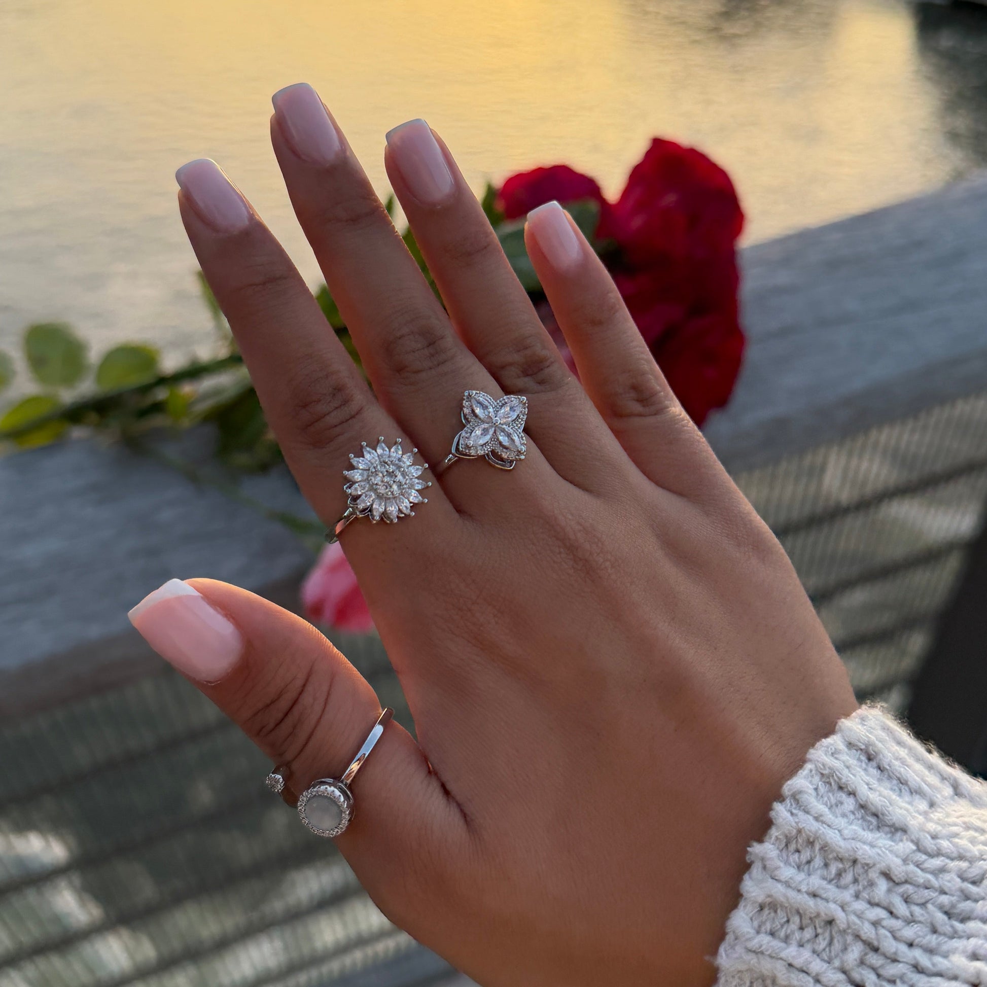 Hand wearing a diamond ring with a sunset and river background
